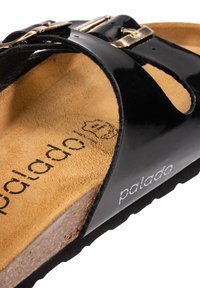 Svart patentläder slide sandal med en dämpad korksula, guldfärgade metallaccenter och en texturerad textillinje.