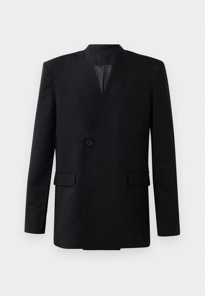 Must mustriga mustriga, millel on ühekordne nööbikinnitus, kaks eesmist taskut ja kõrge krae. Sile kangas tekstuur.