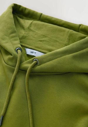 Sweat à capuche vert olive avec cordon de serrage, doté d'une texture douce et d'une étiquette portant la mention "NEXT" à l'intérieur de l'encolure.
