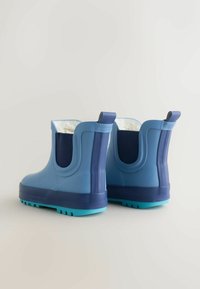 Stivali ankle in gomma blu con una base blu scuro, suole con grip testurizzato e pannelli elastici laterali. Interno foderato per isolamento.