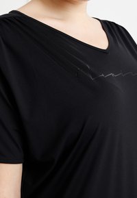 Black V-neck T-shirt with short sleeves, featuring pleated detailing across the chest and a smooth, stretchy fabric texture.