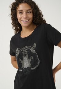 T-shirt en coton noir avec un motif en strass argenté représentant une tête de lion à l'avant, avec un col rond et des manches courtes.
