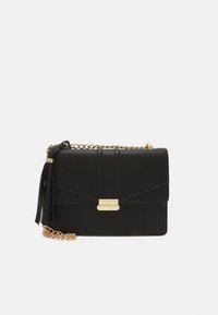 Borsa a tracolla nera in pelle con una tracolla in catena dorata, dotata di un pon-pon, hardware dorato e cuciture diagonali sul pattina.