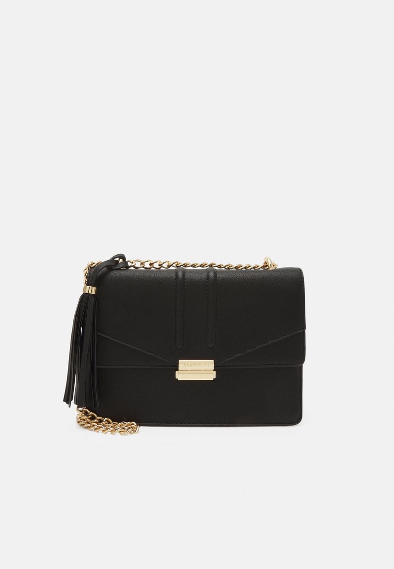 Borsa a tracolla nera in pelle con una tracolla in catena dorata, dotata di un pon-pon, hardware dorato e cuciture diagonali sul pattina.