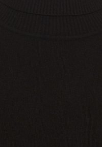 Schwarzer, gerippter Strickpullover mit hohem Kragen und weicher Textur. Der Stoff ist elastisch und eng gewebt.