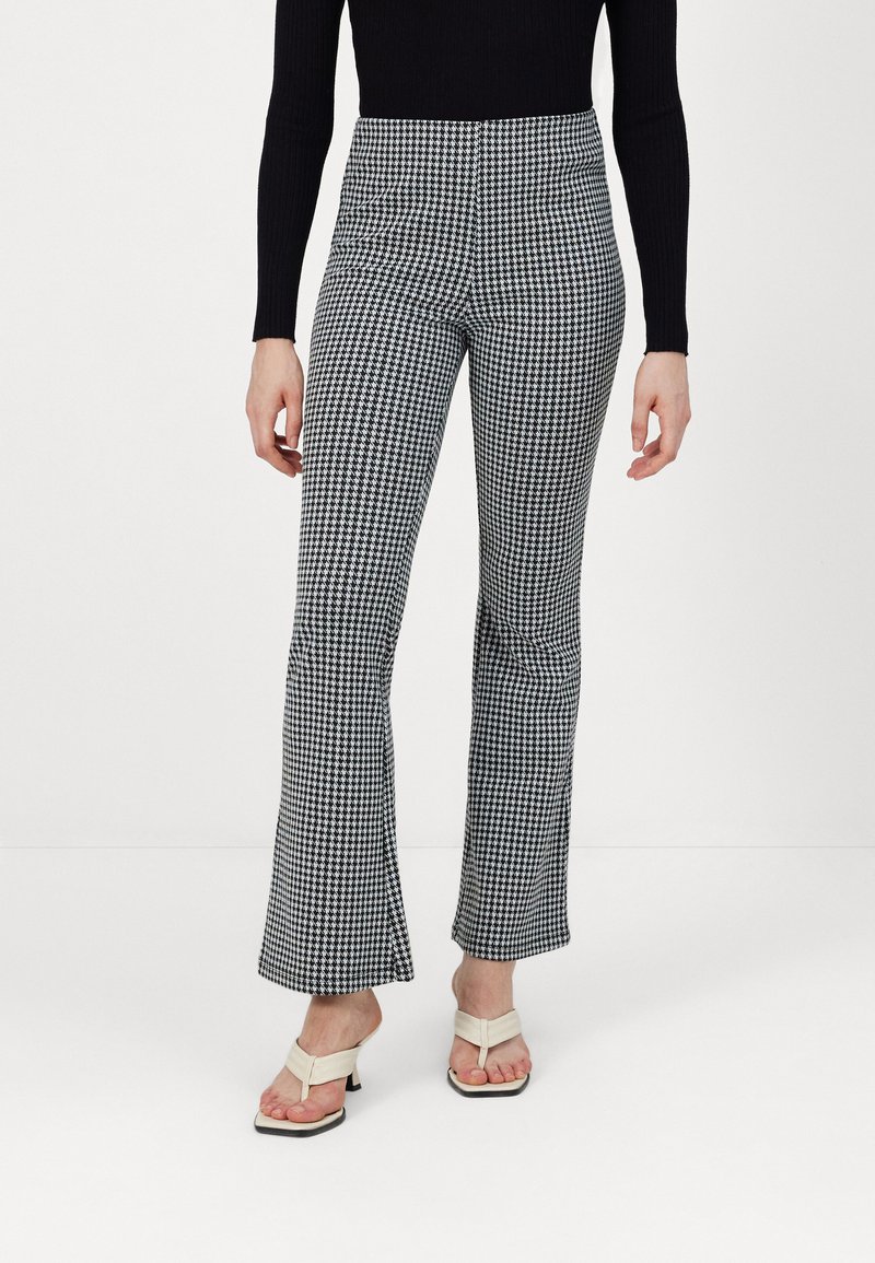 Zwart-wit houndstooth flared broek met een hoge taille, gemaakt van textuurstof. Heeft voorzakken en uitlopende zomen.