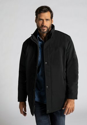 Zwarte buitenjas met een hoge kraag en drukknoopsluiting, voorzien van zakken en een gladde textuur, gelaagd over een denim overhemd.