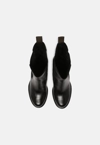 Bottes de cheville en cuir noir avec une finition lisse, des panneaux latéraux élastiques et une languette pour un enfilage facile, avec un bout légèrement arrondi.