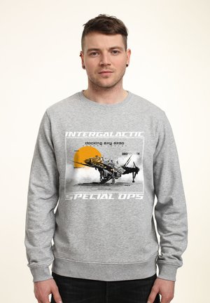 Šedá mikina s grafickým potiskem vesmírné lodi a textem "INTERGALACTIC SPECIAL OPS" a "docking bay 538." Měkká textura, design s kulatým výstřihem.
