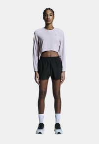 Ljusrosa kortärmad topp med långärmar, svarta shorts med elastisk midja, vita strumpor och svarta löparskor. Enkel design, figursydd stil.