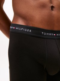 Mustad puuvillased bokserid, millel on pehme vöökoht, millel on valge kiri "TOMMY HILFIGER" ja punane ja sinine logo aktsent.