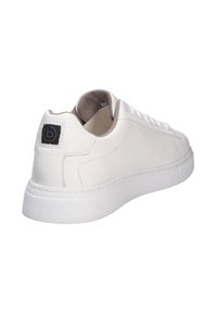 Baskets en cuir blanc avec une finition lisse, bout rond et semelle en caoutchouc texturé. Présente un patch logo noir sur le talon.