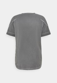 Szara koszulka z krótkim rękawem o gładkiej fakturze, z okrągłym dekoltem i kontrastującymi przeszyciami wzdłuż szwów na ramionach.