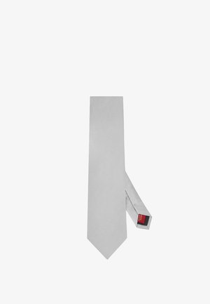 Prosty jasnoszary krawat położony na płasko z widoczną czerwoną i czarną metką marki na tylnej pętli.