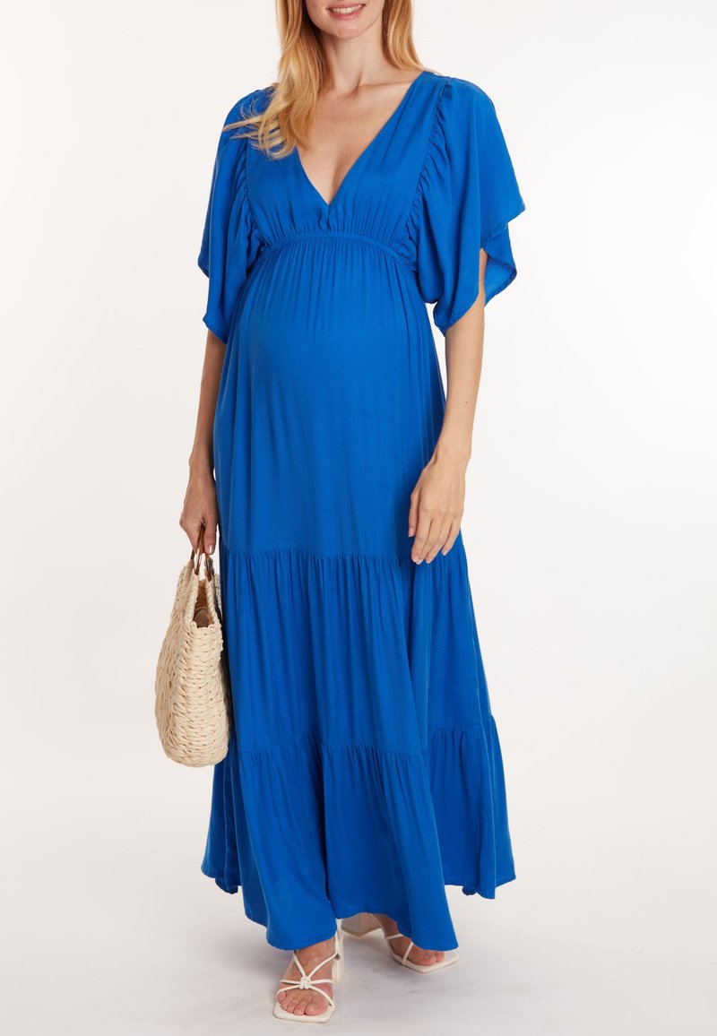 Robe maxi de maternité bleue avec un décolleté en V profond, des manches courtes en volants et un ourlet à niveaux. Le tissu est doux et fluide, mettant en valeur la silhouette.