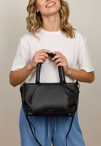 Czarna skórzana torebka o zorganizowanej konstrukcji, z dwoma górnymi uchwytami i odpinanym paskiem. Gładka tekstura z subtelnymi detalami w postaci przeszyć.