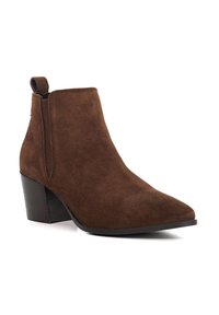 Brown suede ankle boot with a pointed toe design, a chunky black heel, and elastic side panels for easy wear. Features a pull tab at the back.