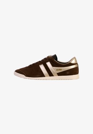 Zapatillas de ante marrón con acentos metálicos dorados, que presentan dos rayas doradas, una suela blanca y un collar acolchado negro. Logotipo de Gola visible.