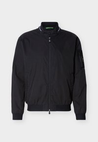 Chaqueta bomber negra con cremallera, cuello alto, puños y bajo acanalados, y un bolsillo con cremallera en la manga izquierda.