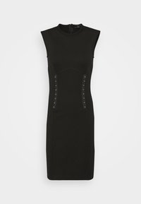 Robe noire ajustée avec un col haut, design sans manches, détail de couture courbée, et rangées verticales de clous en métal sur les côtés.