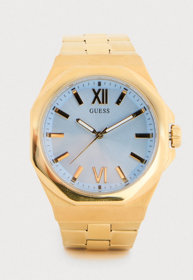Orologio in metallo dorato con cassa ottagonale, quadrante azzurro chiaro, indici delle ore dorati e bracciale a maglie. Presenta una visualizzazione con numeri XII e VI.
