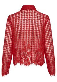 Červená krajková bunda so vzorom houndstooth. Má dlhé rukávy, špicatý golier a rozstrapkané okraje na leme a manžetách.