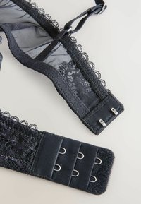 Crni čipkasti i mrežasti remen s izrezanim rubovima, s kukama i očicama za podešavanje. Mekana tekstura, elegantni dizajnerski detalji.