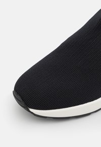 Sneaker in rete nera con punta arrotondata, suola intermedia bianca e superficie strutturata. Presenta un design senza cuciture e una suola esterna in gomma flessibile.