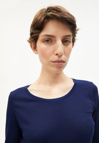 Tiefblaue Langarmbluse mit Rundhalsausschnitt, aus weichem Material gefertigt. Der Stoff wirkt glatt und leicht dehnbar. Keine sichtbaren Muster.