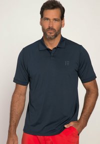 Mørkeblå polo-shirt lavet af glat stof, med klassisk krave og korte ærmer, samt et diskret logo trykt på brystet.