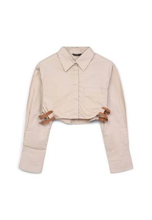 Camicetta beige corta con maniche lunghe, colletto con bottoni, taschino frontale e cinturini in pelle all'orlo per una vestibilità regolabile. Tessuto con texture liscia.