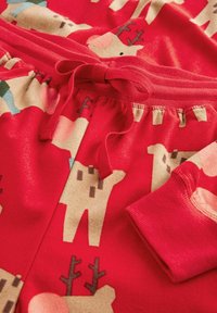 Rode pyjamabroek met een speels patroon van lichtbruine beren met hoorntjes. Het materiaal lijkt zacht en comfortabel, met een tailleband met trekkoord.