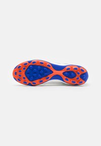 Sole di scarpa sportiva bianca con tacchetti di trazione blu e arancione. Presenta forme ovali per aderenza, una consistenza liscia e un netto contrasto di colori.