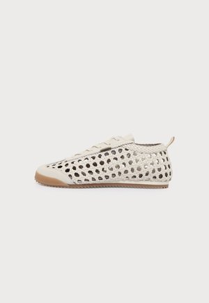 Sneaker crema bassa in tessuto intrecciato con cerniera laterale, suola in gomma e linguetta posteriore su sfondo chiaro uniforme.