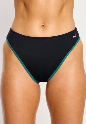 Bas de bikini noir avec bordure verte porté sur les hanches, avec un petit logo Puma rose sur le côté droit.