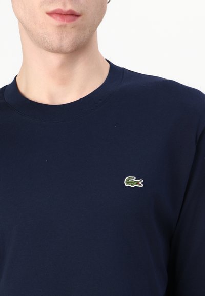 Sweatshirt en coton marine avec un col rond et un petit logo crocodile vert brodé sur la poitrine. Texture douce, design décontracté.