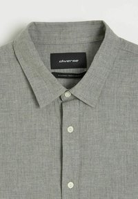 Szara koszula z kołnierzykiem, zapinana na guziki, z białymi guzikami, z etykietą marki "diverse" i oznaczeniem rozmiaru XL wewnątrz kołnierza.