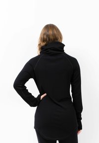 Schwarzes Langarmoberteil mit hohem Kragen, das eine taillierte Silhouette und gerippte Textur aufweist und über die Taille hinausgeht mit einem geschwungenen Saum.