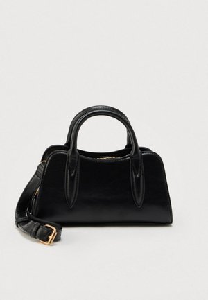 Schwarze Ledertasche mit doppelten Griffen und einem abnehmbaren Schulterriemen mit goldener Schnalle, vor einem schlichten weißen Hintergrund.