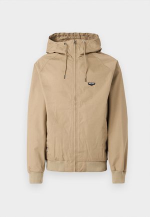 Beige zip-up jacket with a hood, ribbed cuffs, and hem. Features a small black logo on the left chest. Smooth fabric with a casual design.
