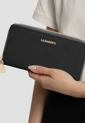 Cartera de piel negra con una superficie texturizada, logo dorado y cierre de cremallera. De mano, con un charm dorado en el tirador de la cremallera.