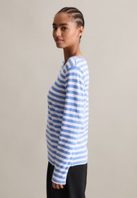 Koszula z długim rękawem w paski wykonana z miękkiego materiału, z poziomymi paskami w jasnoniebieskim i białym kolorze. Ściągacze przy mankietach oraz okrągły dekolt.