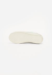 Suola di sneaker bianca con motivo testurizzato, caratterizzata da un bordo liscio e una leggera curvatura. Il materiale sembra essere gomma con buona aderenza.