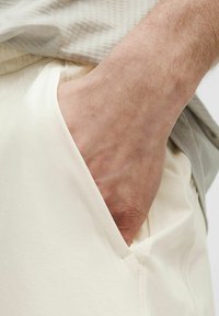 Heledad, pehmed kangad, millel on küljetasku, ja käsi toetub sinna sisse. Materjal on sile ja paindlik.