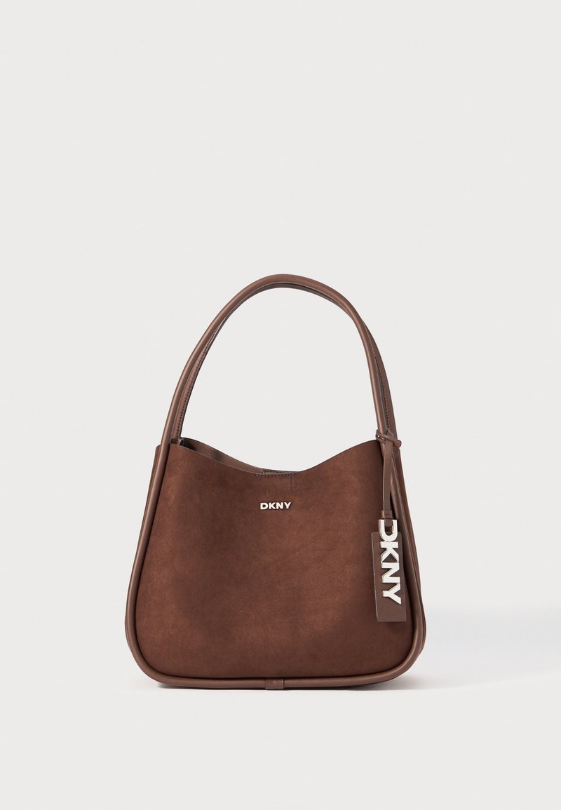 Borsa a tracolla in camoscio marrone con una texture liscia, forma curvata e una maniglia singola. Presenta un logo in argento e un'etichetta con il nome del marchio.