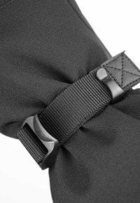 Black nylon strap with a plastic buckle, featuring a woven texture and stitched accents, secured in a knotted position.