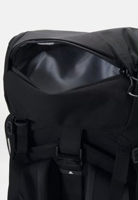 Schwarzer Rucksack mit einem oberen Reißverschluss, ausgestattet mit einem glatten, silbernen Innenfutter. Verfügt über verstellbare Träger und einen seitlichen Schnallenverschluss für sicheren Halt.
