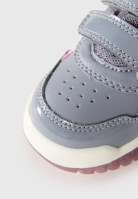Gray sneaker with velcro straps, textured leather upper, perforated toe, and translucent pink rubber sole.