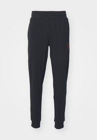 Pantalons de survêtement noirs en mat�ériau doux et extensible. Dotés d'une taille élastique et de poignets ajustés, avec un petit accent logo rouge.