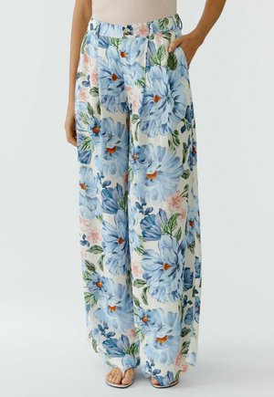 Wijde broek met blauw- en roze bloemenprint, hoge taille en zijzakken, gedragen met een beige top en open-toe sandalen.